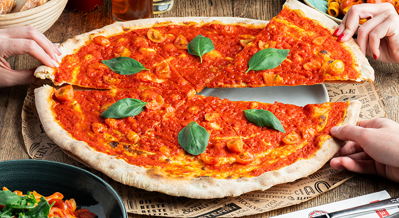 Pizza Marinara Speciale auf einem Holztisch und Hände nehmen sich ein Stück